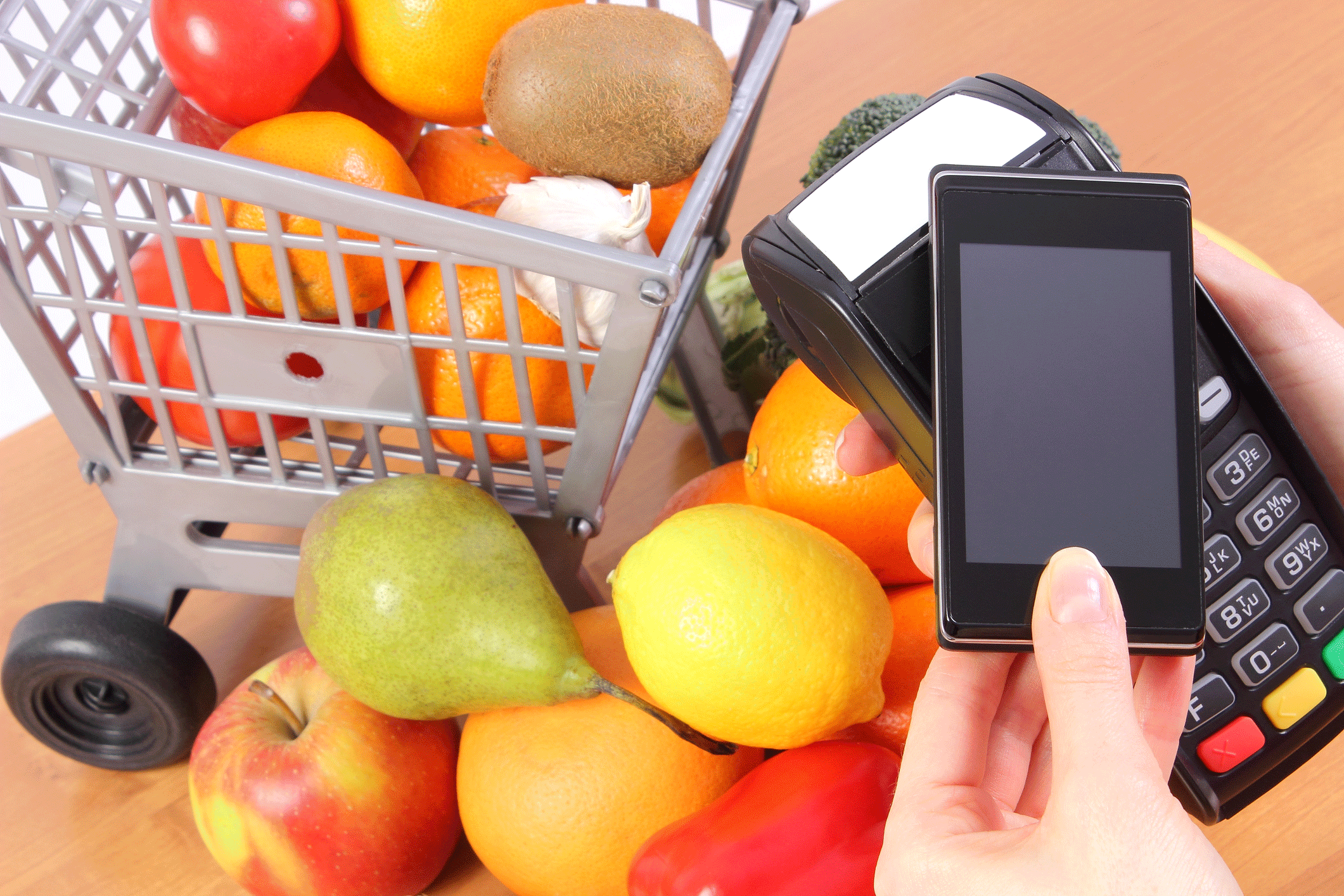 Picture of person buying fruits using phone and NFC wireless pay terminal.